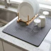 Dish drying mat for kitchen counter holding a dish rack, glasses and a mug on granite