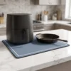 Heat resistant kitchen counter mat under an air fryer and cast iron skillet on marble