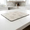 Kitchen counter mat with printed fabric top and rubber base on a white quartz countertop